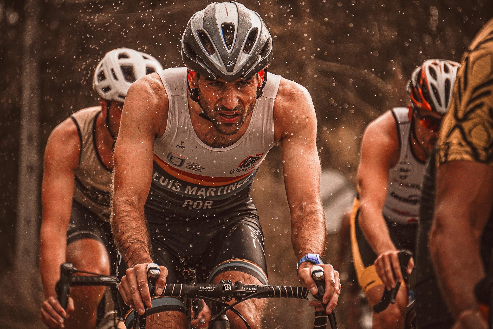 Determined athletes compete in a rain-soaked cycling race, pushing through with endurance.